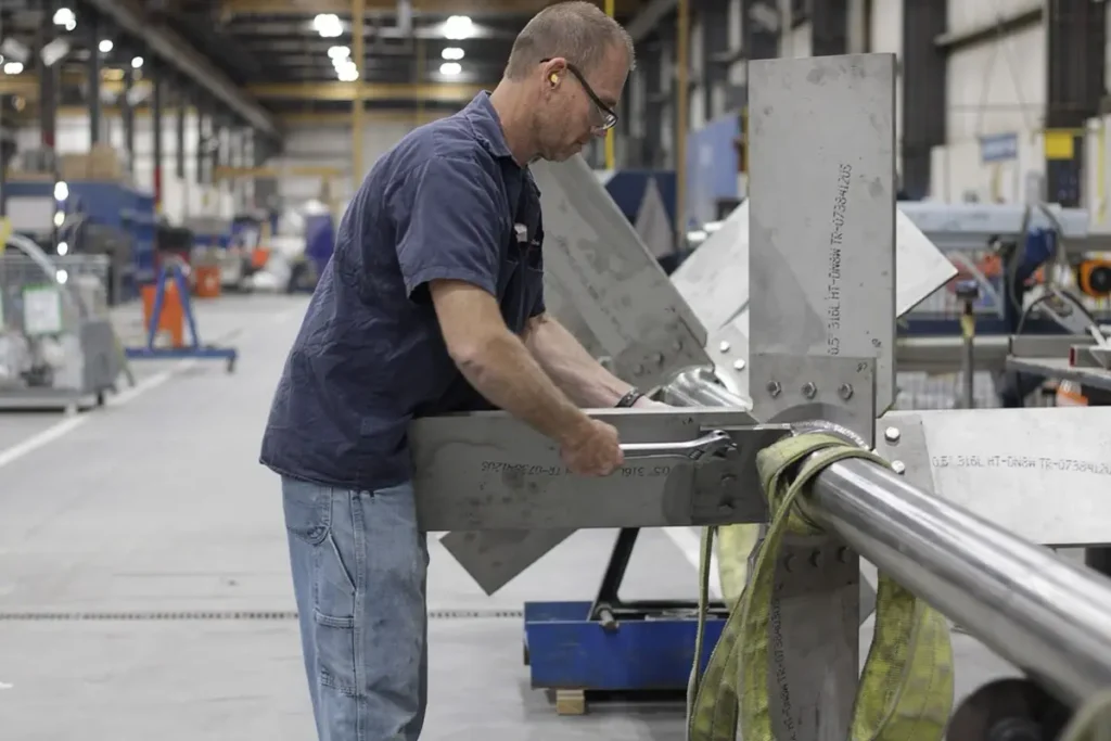 Watson technician in safety glasses and ear protection fitting an impeller on a stainless steel agitation tank