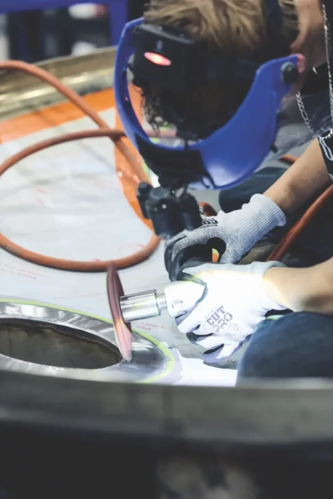 Watson technician polishing a nozzle on a stainless steel tank head