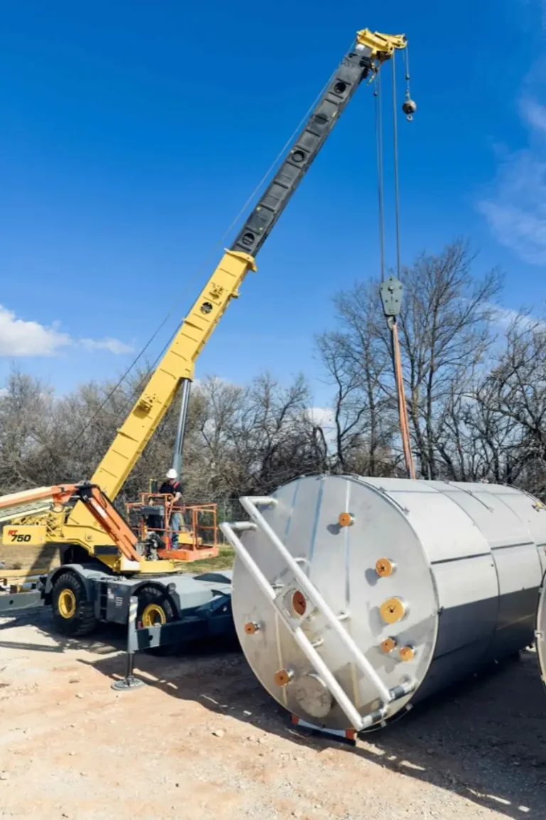 Crew using a crane to set a field fabricated stainless steel tank on the customer's site