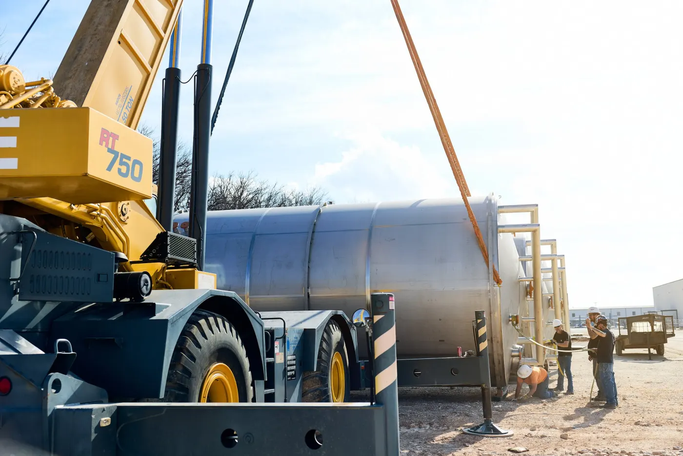 Crane lifting a large stainless steel tank in the Watson yard for shipment
