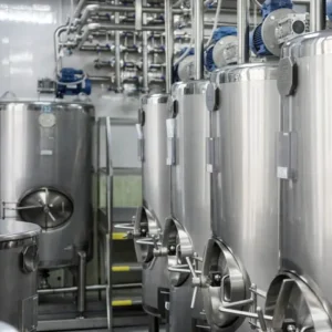 Stainless steel dairy processing tanks and piping inside a processing plant