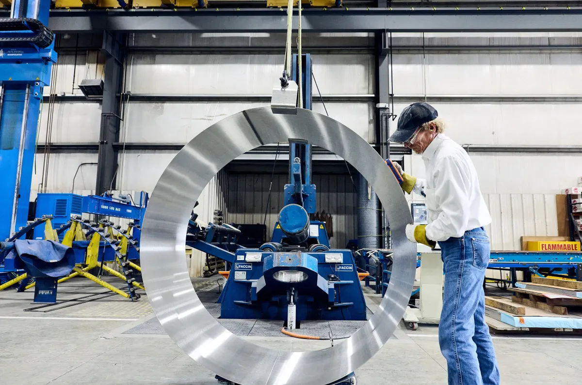 Watson technician in safety gear inspecting a stainless steel tank component